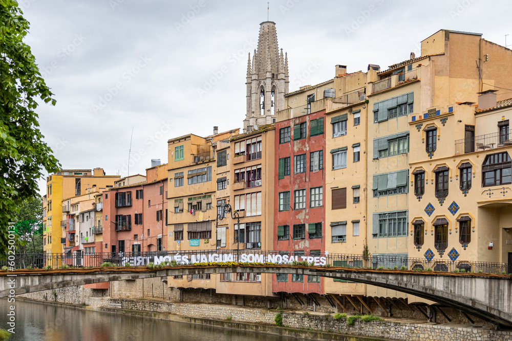 Girona, Spain - May 13th, 2023: TEMPS DE FLORS - Flower Time. Princess bridge with views of the Cathedral and the colorful houses of Onyar river on a rainy day. Banner 
