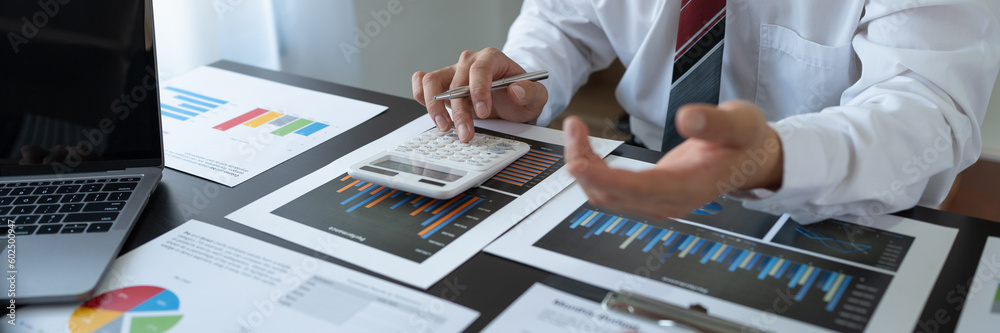 Team of business people working with calculator to calculate financial figures and analyzing sales data on economic growth chart. banking and finance Digital Marketing and Business Strategy.