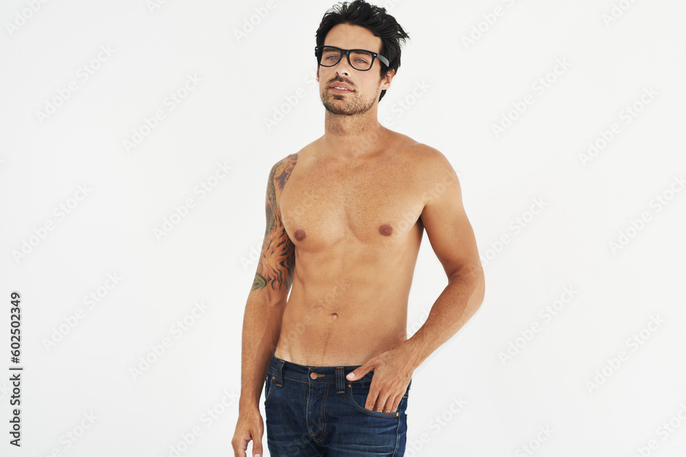 Portrait, shirtless and glasses with a sexy man model in studio on a white background for masculine desire. Body, tattoo and manly with a handsome young male nerd posing topless for rugged sensuality