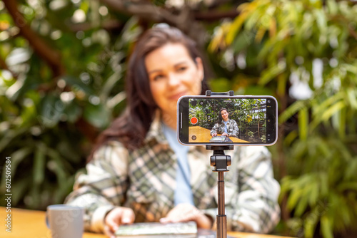 A woman blogger records herself on a smartphone camera standing on a tripod. Freelancer, communication via the Internet.