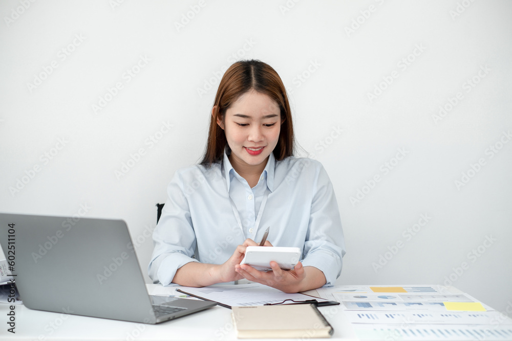 Beautiful young asia businesswoman’s sitting in the office room and using a calculator to calculate the profit figure. Beautiful young asia businesswoman’s sitting in the office room and using a calculator to calculate the profit figure.