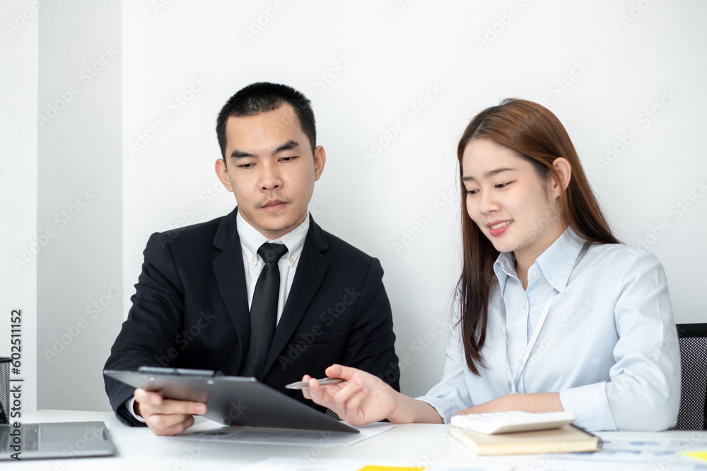 Two business people sitting at workplace and discussing about earnings on a graph to plan investments. Two business people sitting at workplace and discussing about earnings on a graph to plan investments.