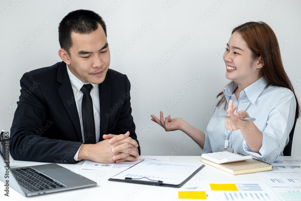 Two business people sitting at workplace and discussing about earnings on a graph to plan investments. Two business people sitting at workplace and discussing about earnings on a graph to plan investments.