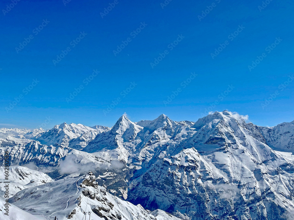 Scenic winter landscape in the Swiss Alps with famous peaks Eiger, Monk and Virgin seen from cabin of Schilthorn cable car cabin on a sunny winter day. Photo taken March 19th, 2021, Switzerland.