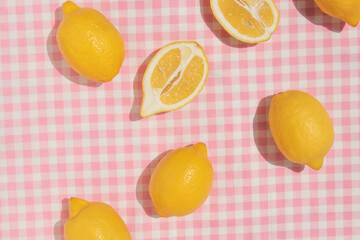 Summer creative layout with lemons on pastel pink plaid  background. 80s or 90s retro aesthetic idea. Minimal summer fruit idea.