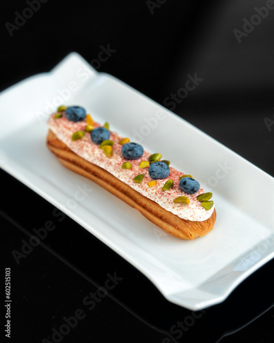 Eclair with topping and blueberry on serving plate