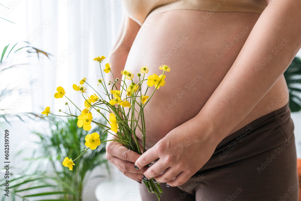 Pregnant woman holding bunch of yellow flowers at home Pregnant woman holding bunch of yellow flowers at home