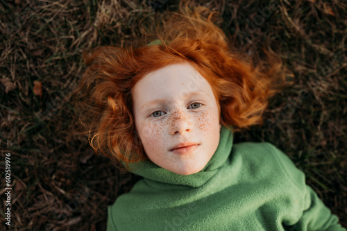 Redhead girl with freckles lying in field photo