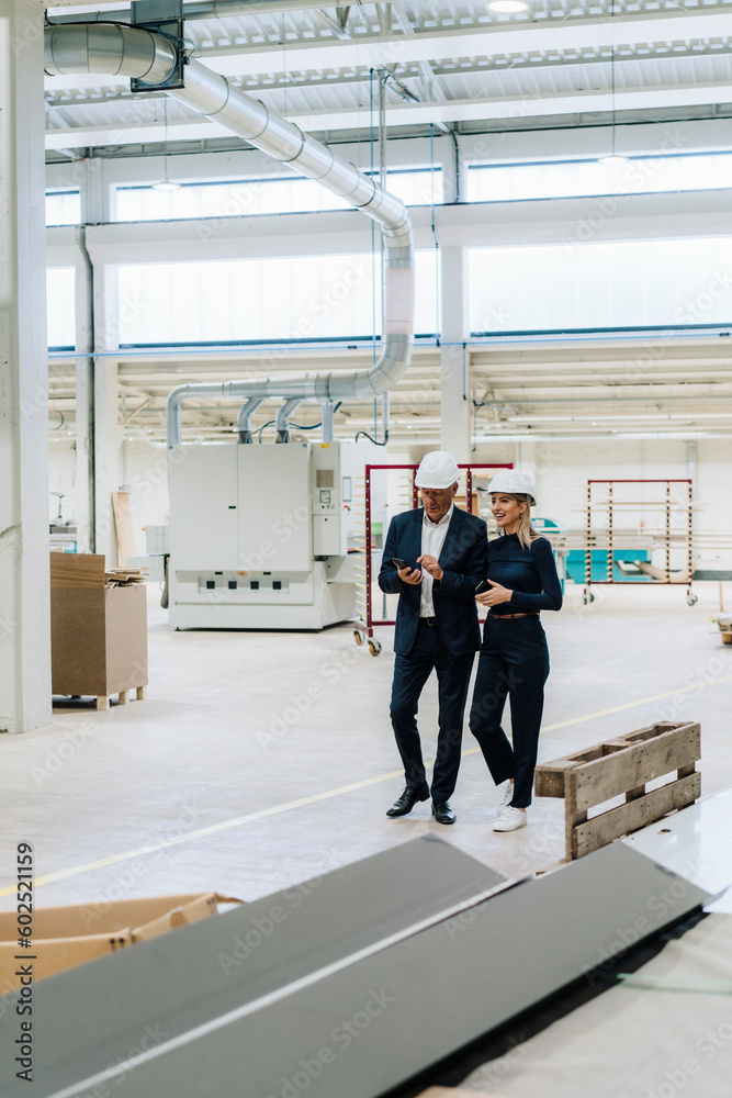 Businessman and colleague walking together in industry Businessman and colleague walking together in industry