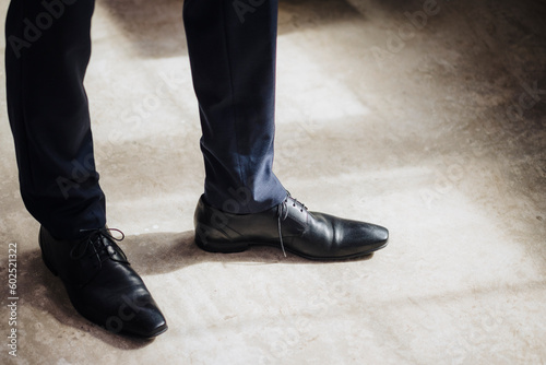 Legs of businessman wearing black formal shoes standing in factory photo