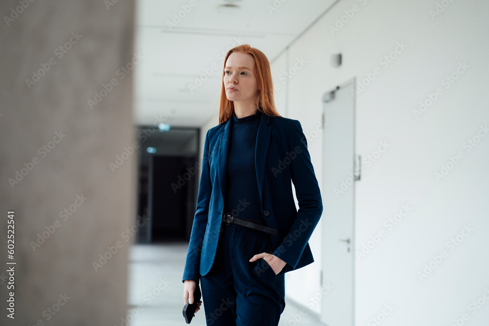 Thoughtful businesswoman with hand in pocket standing at office Thoughtful businesswoman with hand in pocket standing at office