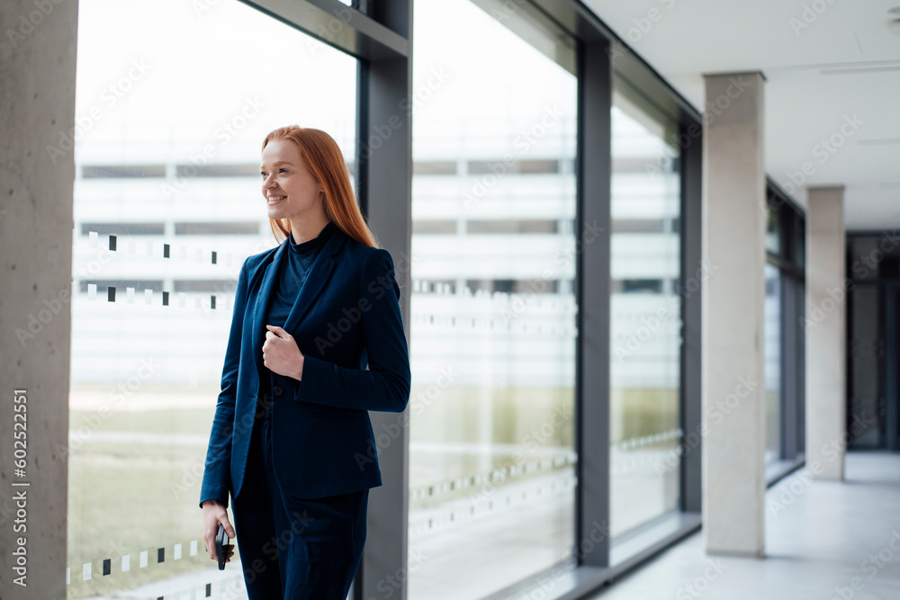 Smiling businesswoman standing near window at office Smiling businesswoman standing near window at office