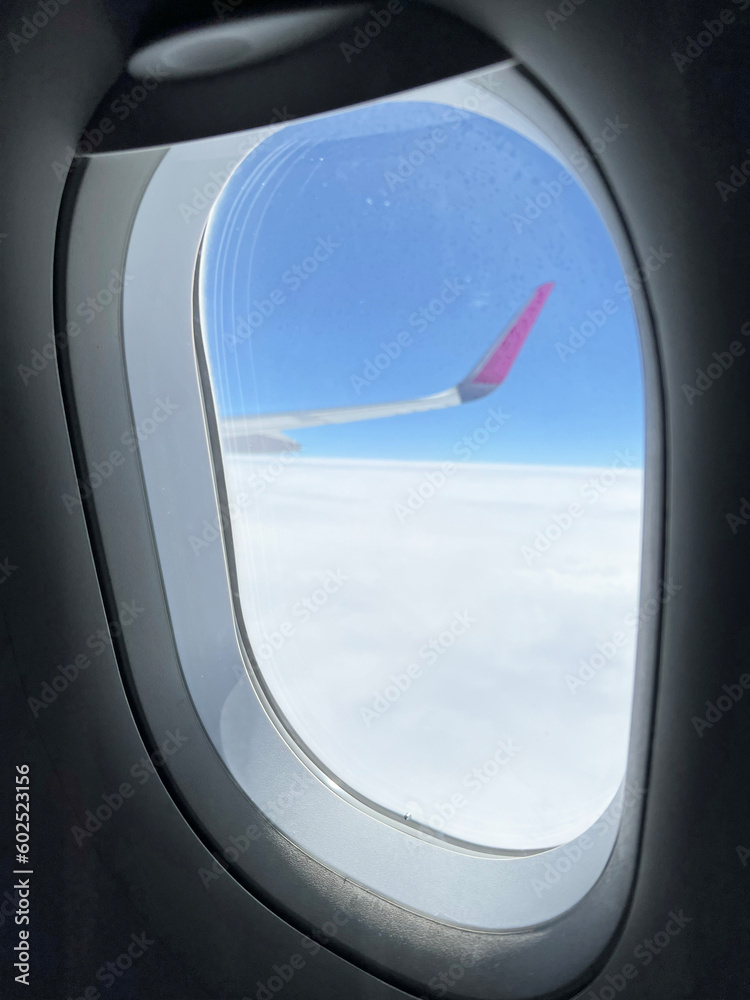 View from the airplane window. Beautiful cloudscape with blue sky. Wonderful panorama above white clouds as seen through window of an plane. View from the airplane window. Beautiful cloudscape with blue sky. Wonderful panorama above white clouds as seen through window of an plane.