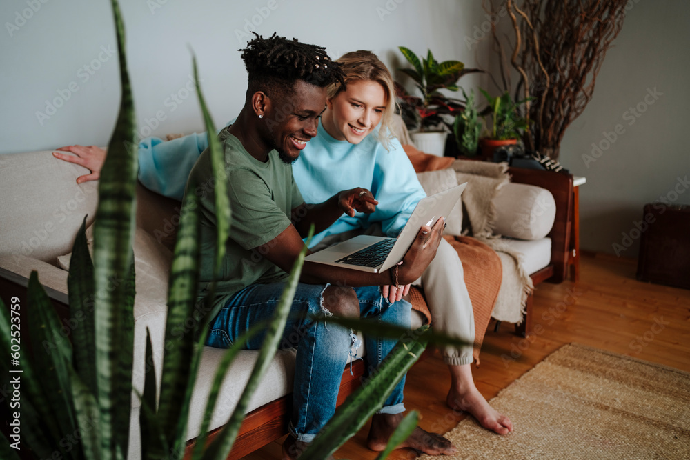Smiling man sharing laptop with girlfriend at home Smiling man sharing laptop with girlfriend at home