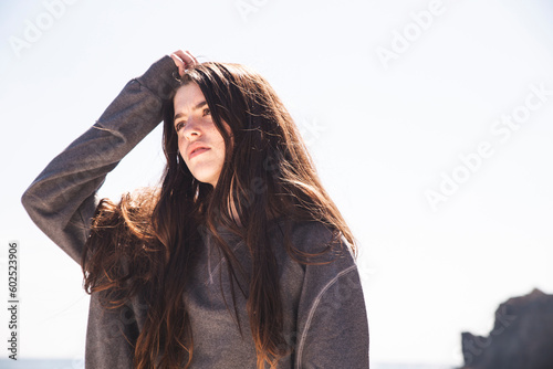 Woman scratching head under sky at sunny day photo