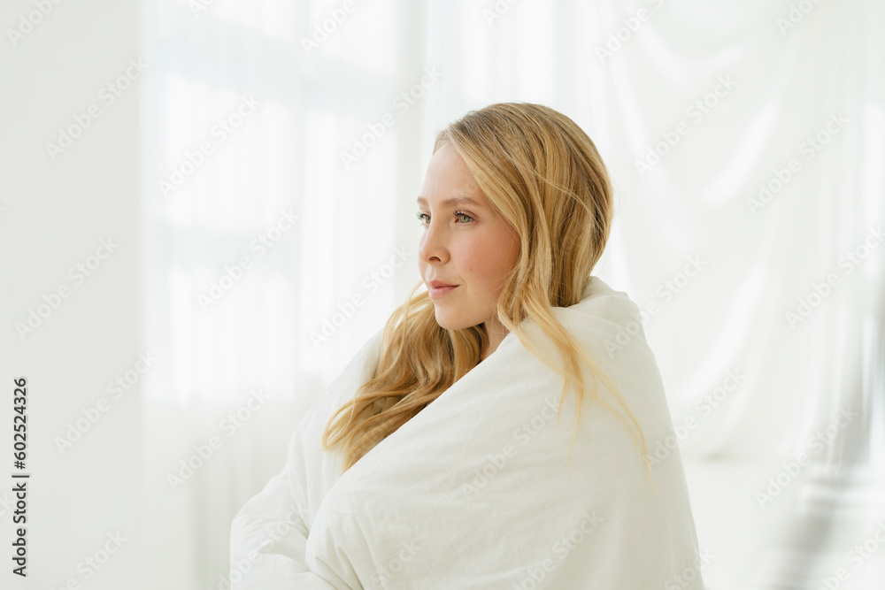 Woman wrapped in white blanket by translucent curtain Woman wrapped in white blanket by translucent curtain