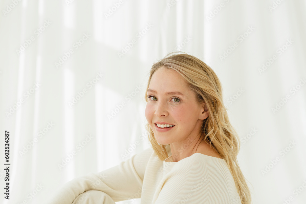 Smiling woman with blond long hair by translucent curtain Smiling woman with blond long hair by translucent curtain