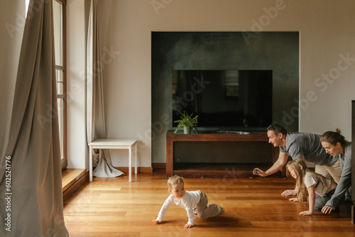Playful family crawling on hardwood floor at home