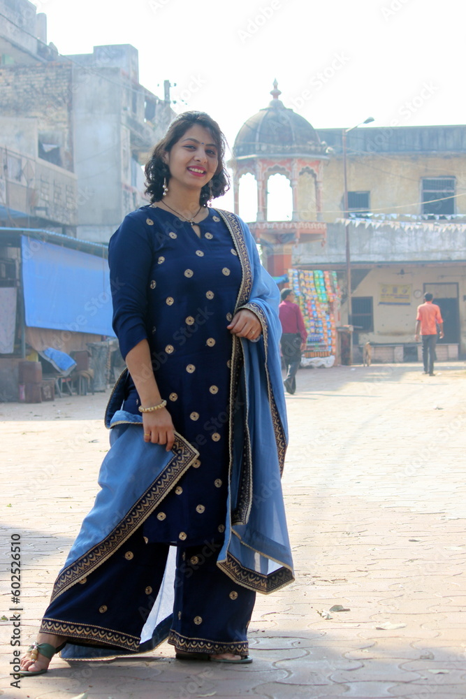 Indian village woman with a short hair in blue indian suit with dupattah standing outside on the street and smiling. On a festival day she is happy and dressed up nice. 