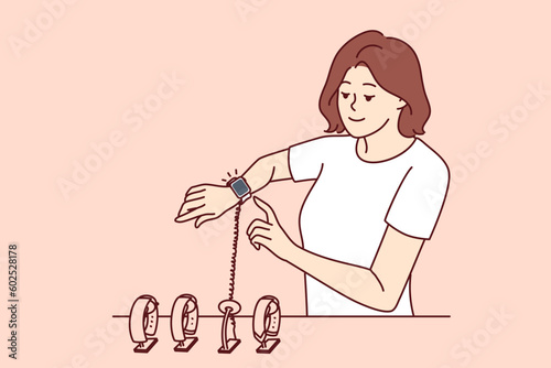 Woman tries on smart watch or fitness bracelet, wanting to choose high-quality device for playing sports and synchronizing with gadgets. Girl in electronics store chooses watch with touch screen