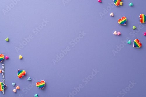 The idea of supporting the LGBTQ+ community is represented in this top view flat lay of symbolic accessories for a pride parade on a violet backdrop with space for text or advertising photo