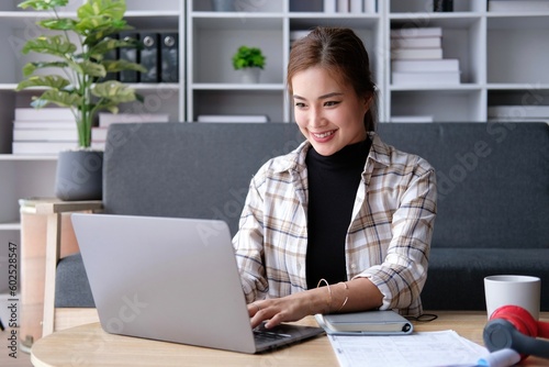 Smiling young asian businesswoman using computer at home office workplace, happy korean employee working on laptop, attractive japanese or chinese woman student studying communicating online with pc