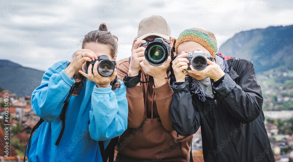 Group of young adult people friends colleagues professional photographers take photo on camera outdoor