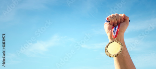 Bild auf Leinwand Gold medal held in athlete hand raised against sky background