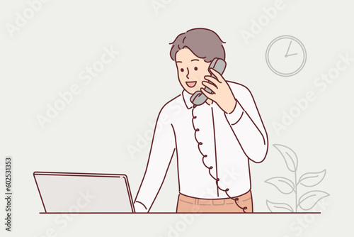 Man receptionist works in hotel and talks on phone with guests or answers questions