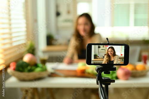 Young woman vlogger recording video content about healthy food on smartphone, selective focus