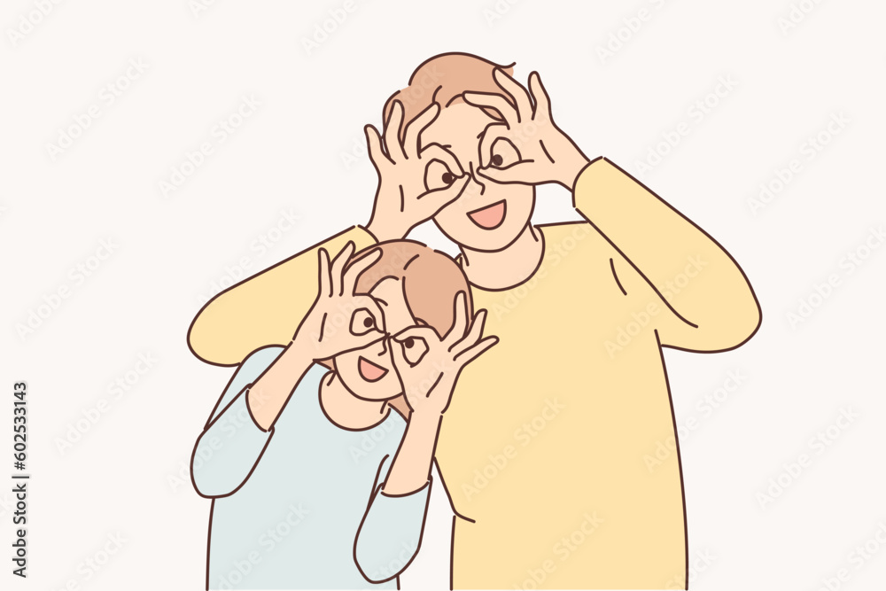 Happy father and daughter make funny faces to have fun putting fingers to eyes instead of glasses Happy father and daughter make funny faces to have fun putting fingers to eyes instead of glasses