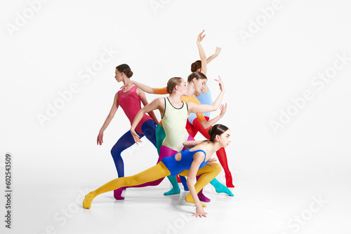 Young girls  ballet dancers in colorful tights and bodysuits training  dancing against grey studio background. Concept of beauty  creativity  classic dance style  elegance  contemporary art