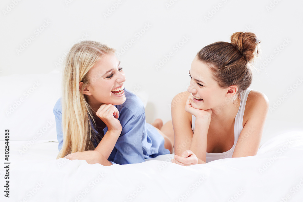 Happy, relax and women in bed laughing together as happiness isolated in a studio white background. Smile, funny and young female friends laugh at a joke and feeling excited in a bedroom
