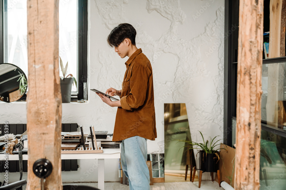 Asian business man working on tablet while standing in office Asian business man working on tablet while standing in office
