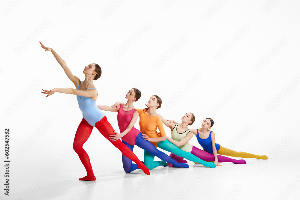 Artistic performance. Group of talented, young girls, ballet dancers in colorful, bright clothes dancing over grey studio background. Concept of creativity, classic dance, elegance, contemporary art