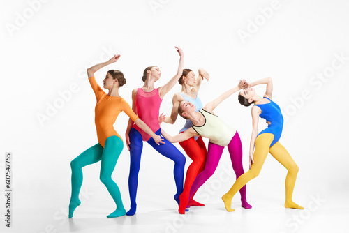 Expressive dance. Stylish, young girls, ballet dancers in bright clothes making performance on grey studio background. Concept of beauty, creativity, classic dance style, elegance, contemporary art