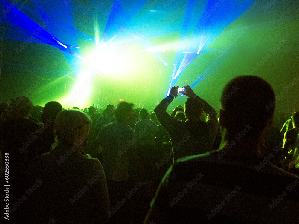 Silhouette of crowd facing illuminated stage at music festival