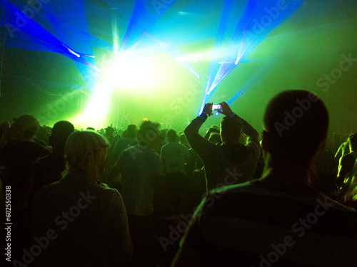 Silhouette of crowd facing illuminated stage at music festival