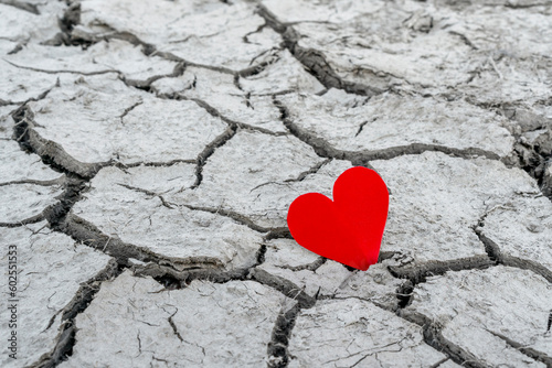 A red paper heart on dry cracked soil