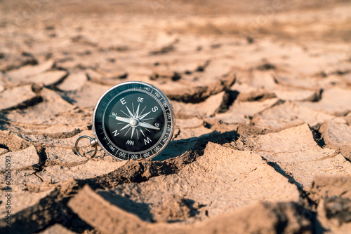 Black compass on the dried and cracked earth background