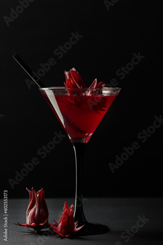 Red martini or cocktail with hibiscus flowers. On a black background, low key.