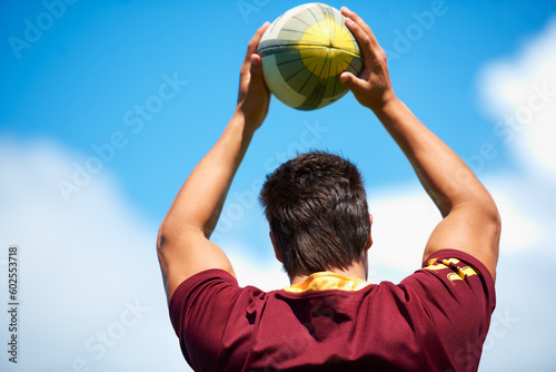 Rugby, sports and man throw ball outdoor on a pitch with blue sky for goal. Headshot of male athlete person playing in sport competition, game or training for fitness, workout or exercise from behind © Cameron Mcdonald/peopleimages.com