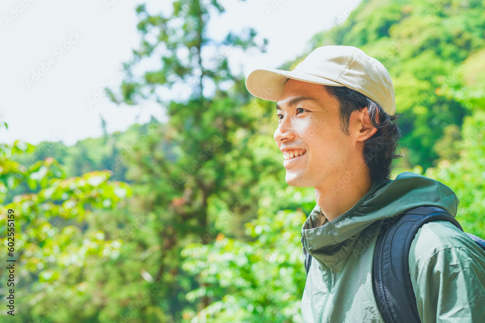 美しい新緑の山でハイキングをする若い男性