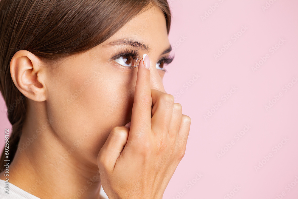 Young woman putting contact lens in her eye, close up Young woman putting contact lens in her eye, close up