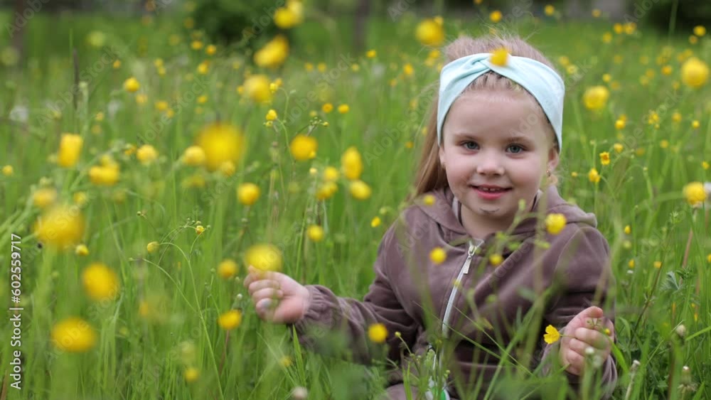 A little girl, 4 years old, sits in the big grass. A child on an uncut lawn. A child is playing on the street. Tall green grass in summer. Childhood in nature. Interested girl A little girl, 4 years old, sits in the big grass. A child on an uncut lawn. A child is playing on the street. Tall green grass in summer. Childhood in nature. Interested girl