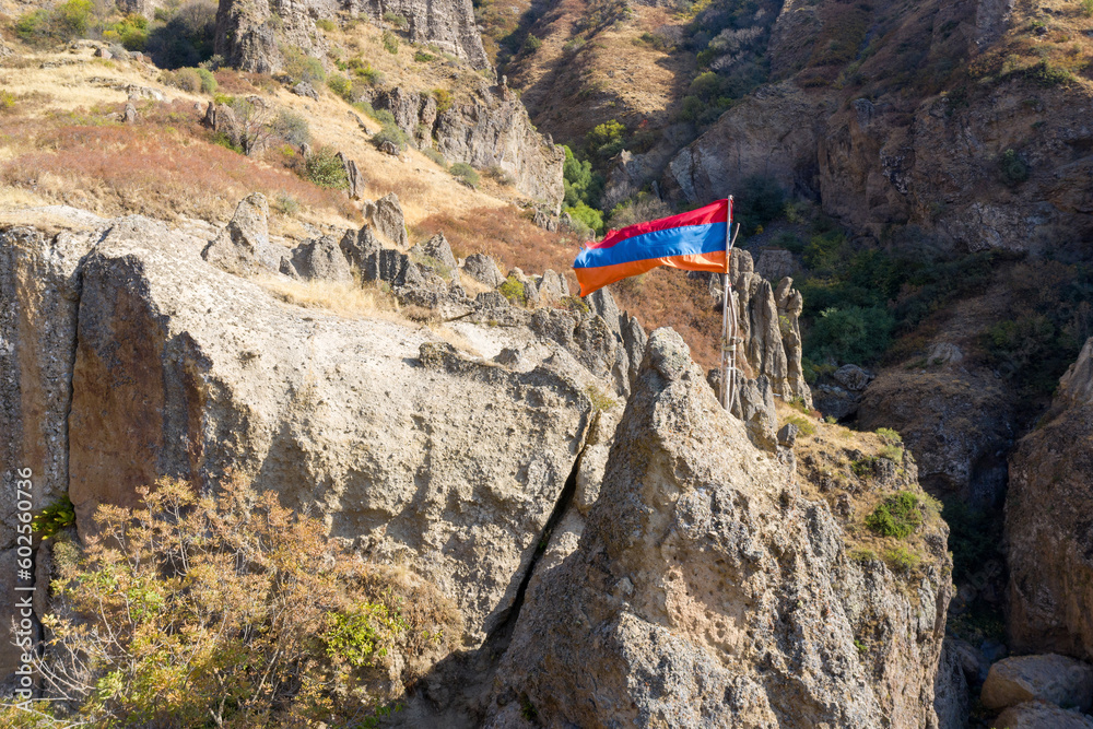 Armenian national flag on the rock on sunny autumn day. Geghard monastery, Azat canyon, Armenia.