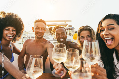 Multiracial friends doing selfie while cheering with wine at boat party outdoor - Focus on african man face