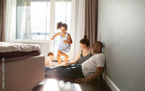 Snapshot of diverse family playing with happy children on floor at home run around in motion, authentic family life, unposed, spontaneous moments of fun and laughter