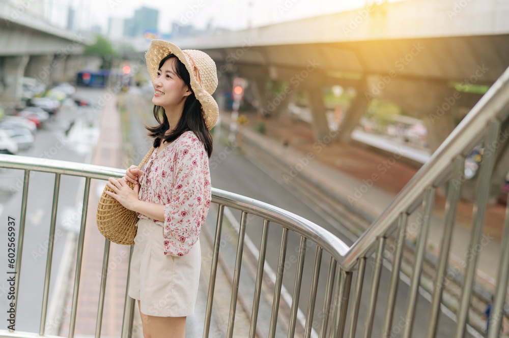 young asian woman traveler with weaving basket happy smiling standing on overpass with railway background. Journey trip lifestyle, world travel explorer or Asia summer tourism concept. young asian woman traveler with weaving basket happy smiling standing on overpass with railway background. Journey trip lifestyle, world travel explorer or Asia summer tourism concept.