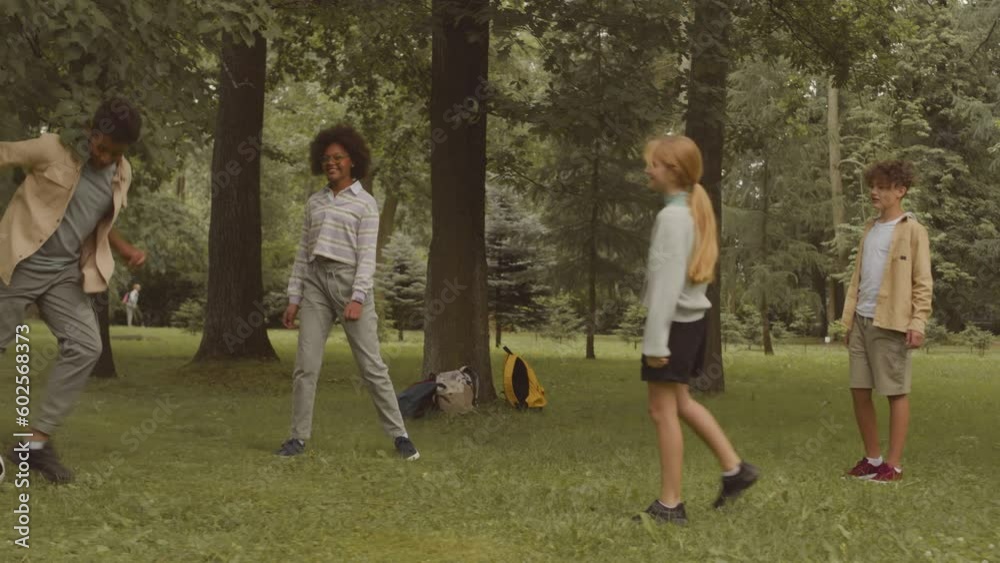 Group of carefree multiethnic children playing football on green grass in park on warm sunny day, spending leisure time together after school Group of carefree multiethnic children playing football on green grass in park on warm sunny day, spending leisure time together after school